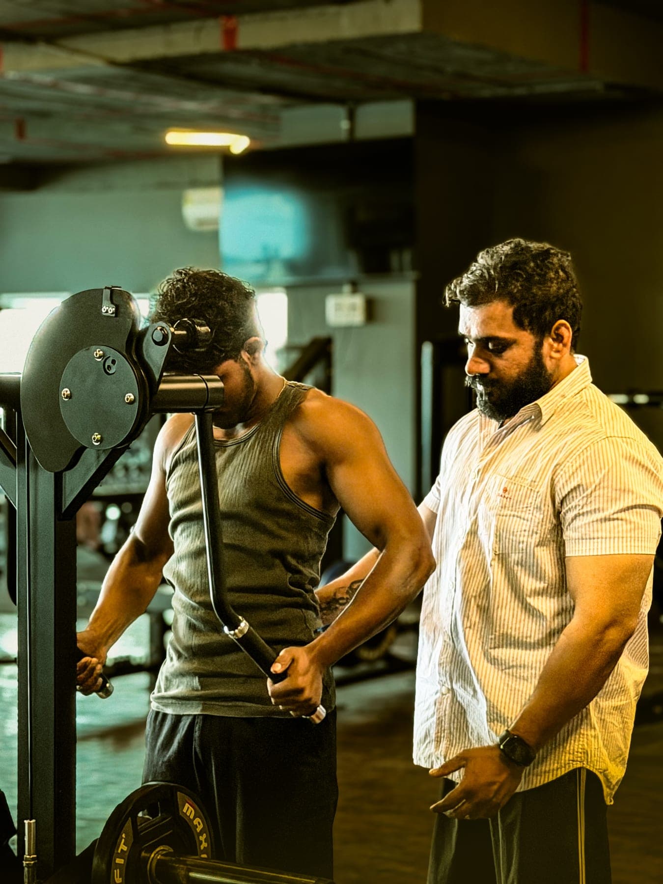 Trainer coaching a member during a cable tricep exercise