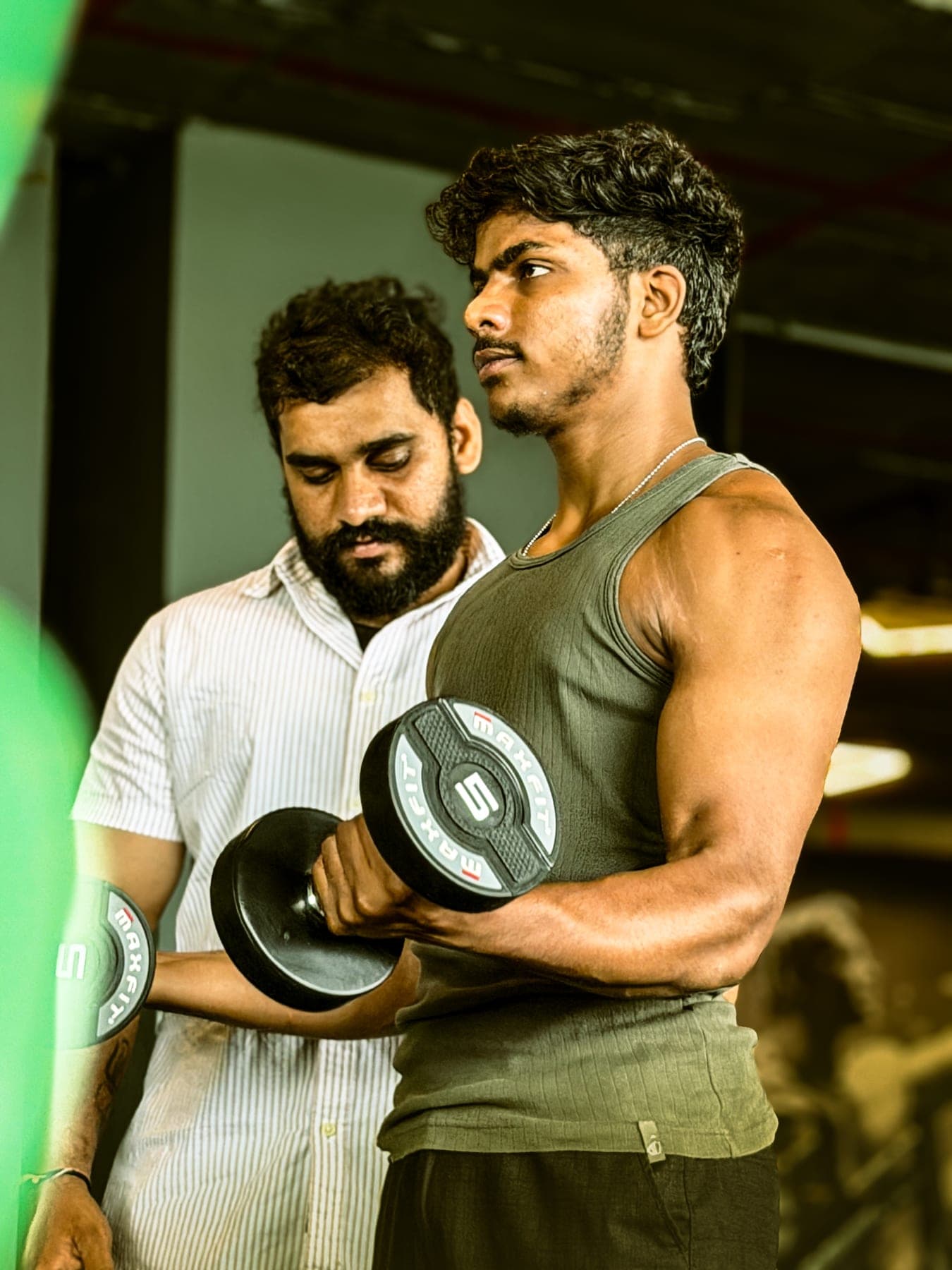 Trainer guiding a member through a dumbbell bicep curl